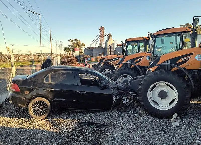 Un auto se despistó, atravesó el cerco de una concesionaria y chocó contra un tractor